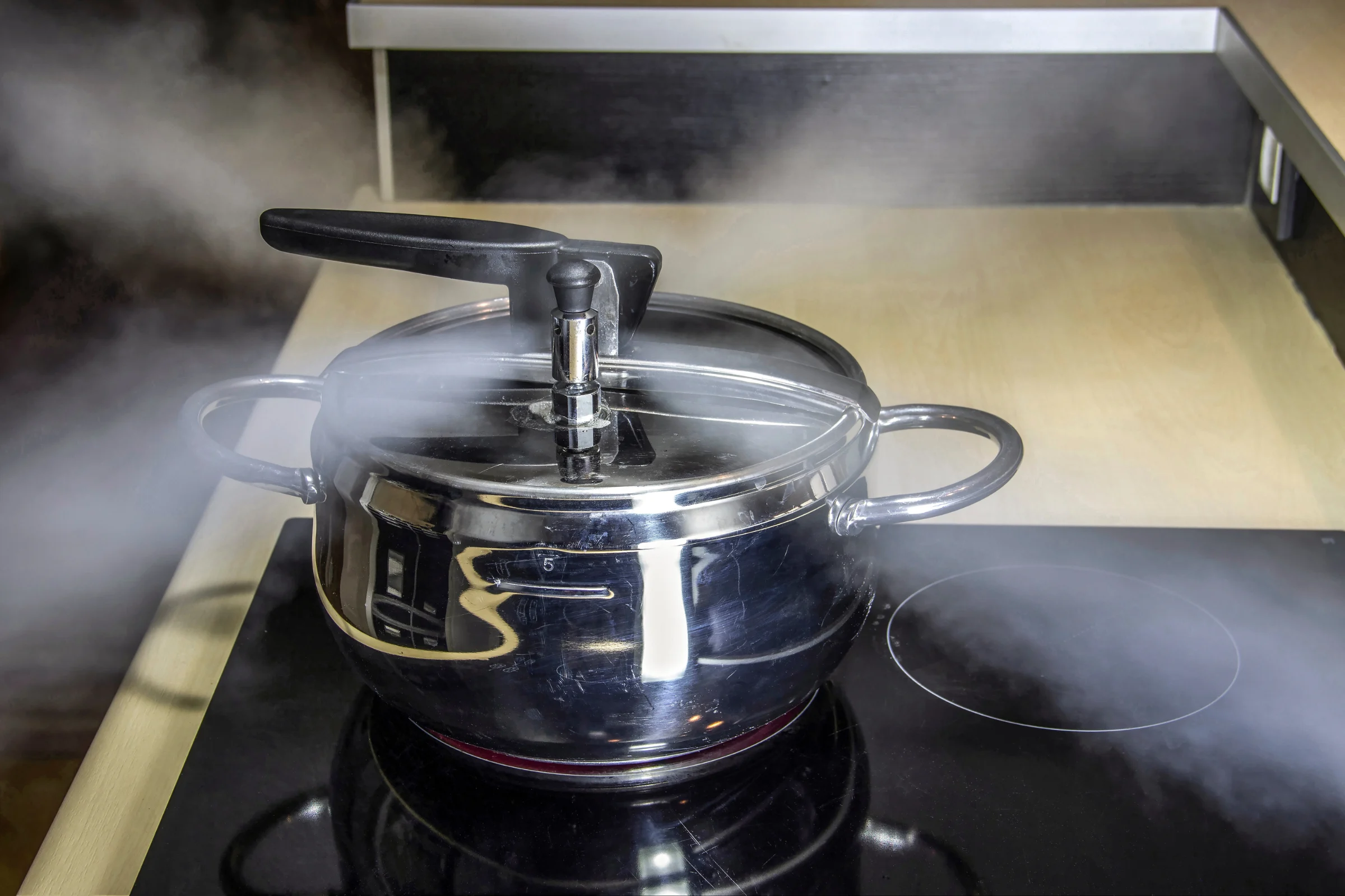 A pressure cooker releasing steam to reduce internal pressure and temperature.