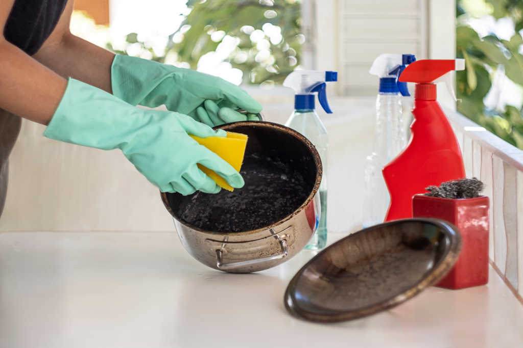 Someone using a combination of cleaning products to degrease their cooking pot.