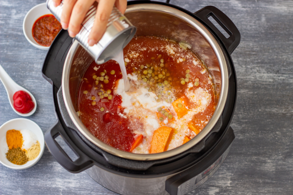 A person pouring cream into an instant pot as part of a recipe.