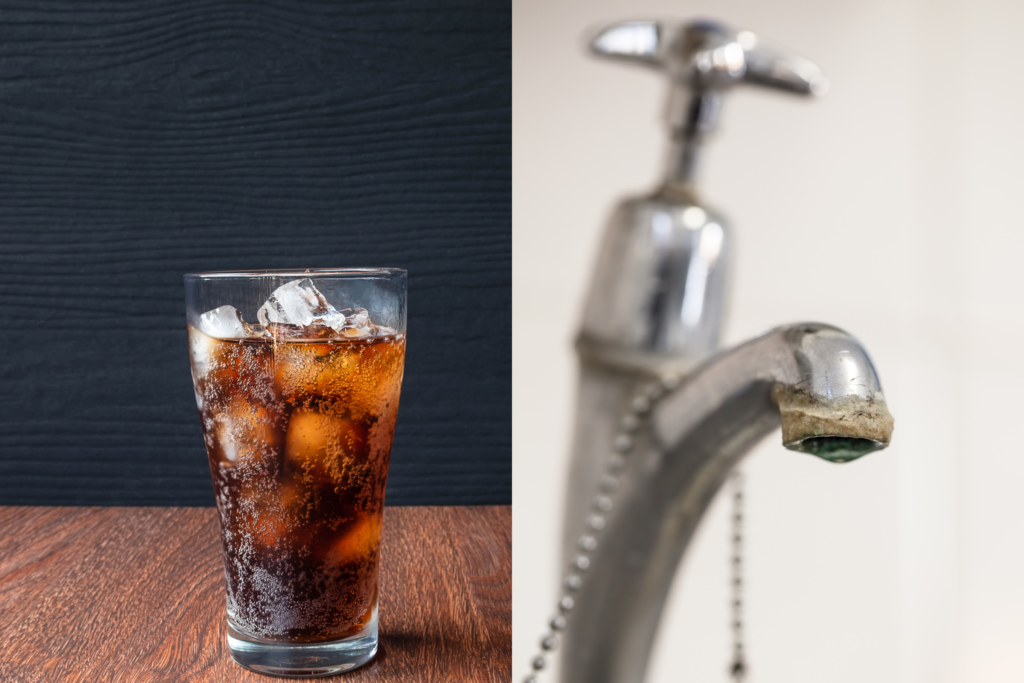 A glass of soda next to a faucet with limescale