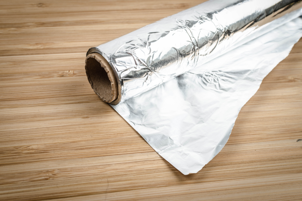A roll of aluminum foil sits on a wooden countertop.