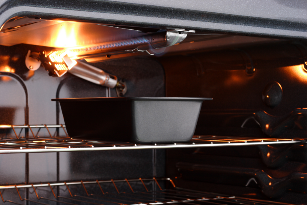 A steel baking tray broils inside a gas oven.