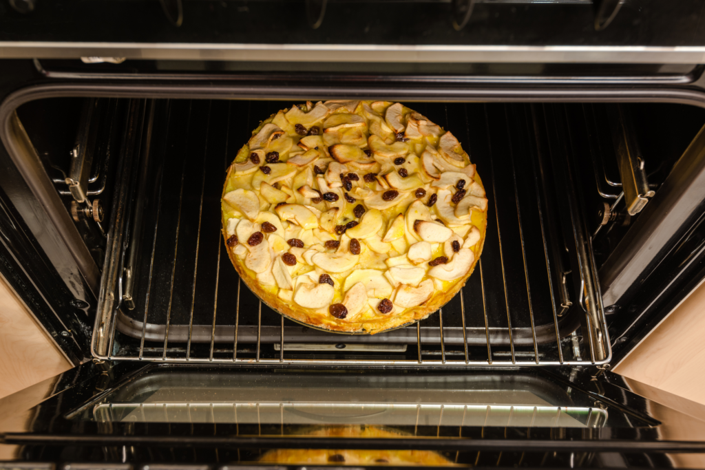 A pie sits inside an open oven to retain heat and finish baking.