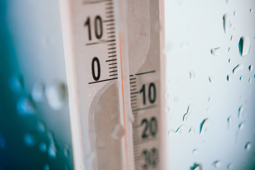A thermometer with condensation around it showing freezing temperatures.