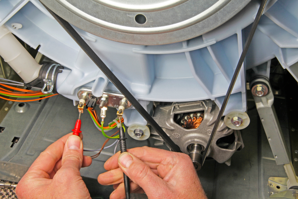 A person repairs a washing machine's wiring.