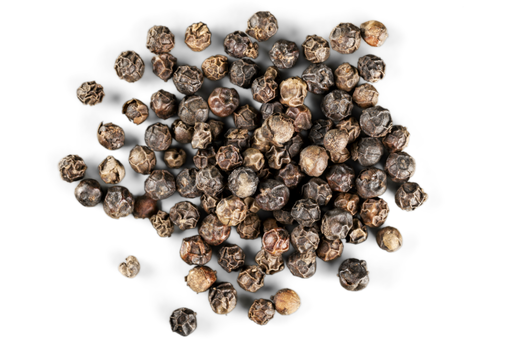 Brown wrinkled peppercorns on a white background to help answer - can you grind peppercorns in a coffee grinder?