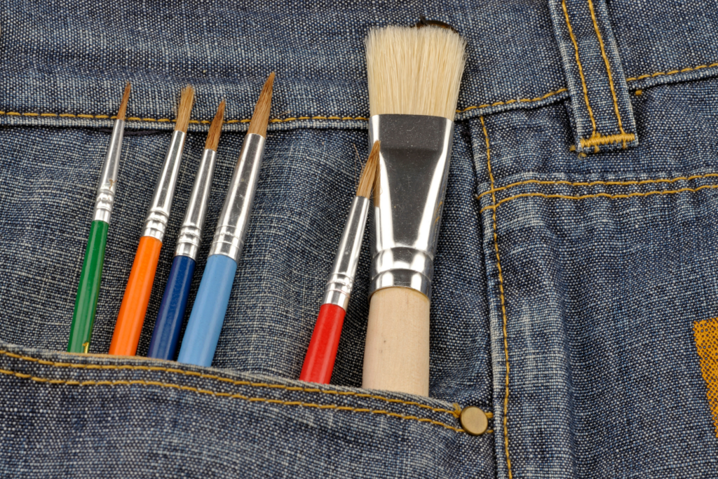 Using paintbrushes or spray paint to paint jeans