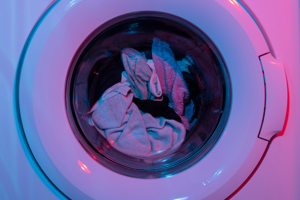 A full washing machine backlit by blueish purple lighting.