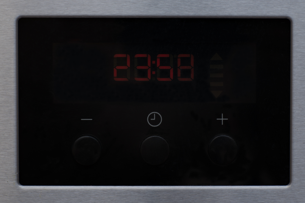 A dimly lit microwave display, showing the time at 23:58.
