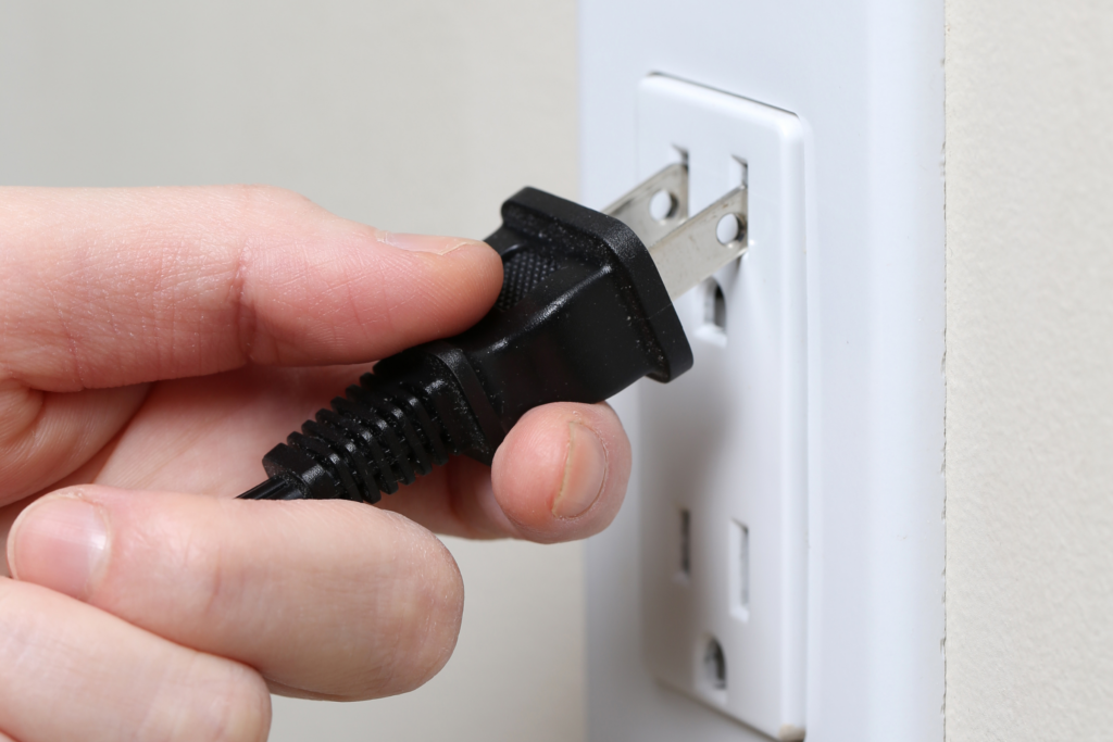 A person inserts a plug into a wall outlet.