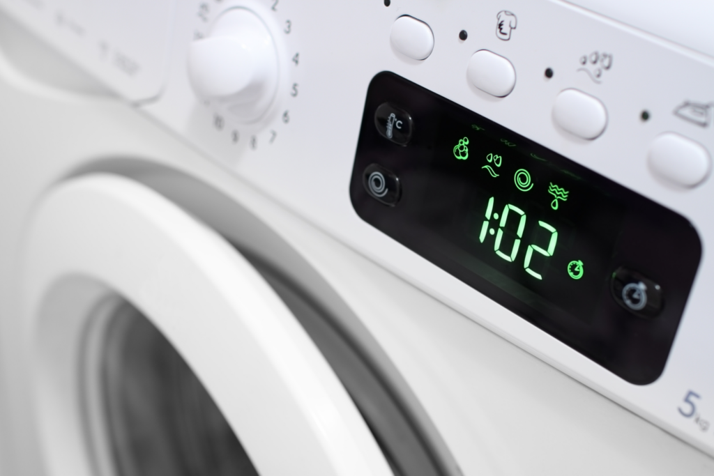 A washing machine display lights up, showing the time remaining at 1:02 (one hour and two minutes).