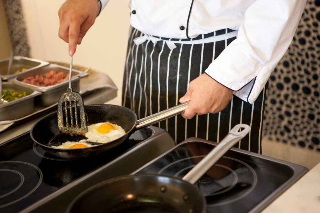 chef using frying pan to fry eggs
